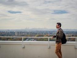 Graduate student standing outside on green roof of CELS overlooking New York City skyline.