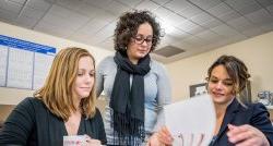 Three staff members of RYTE Institute looking at document.